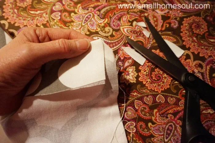 Clipping fabric corners before sewing hem of curtains.