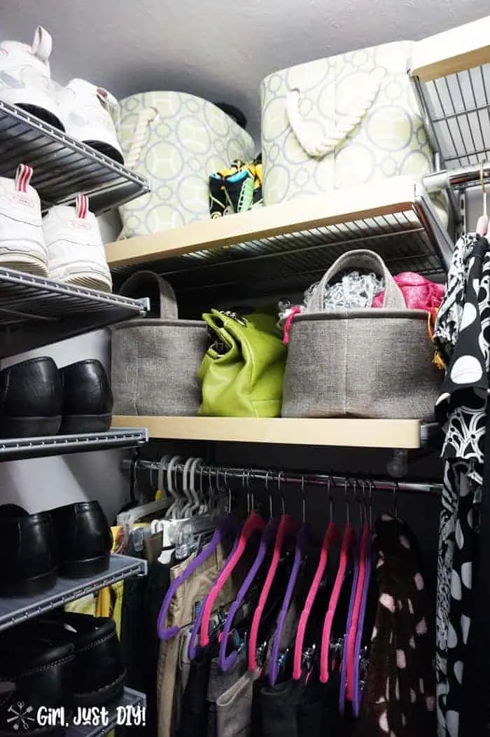 Fabric bins filled with scarves and purses on shelves between clothes and shoes.