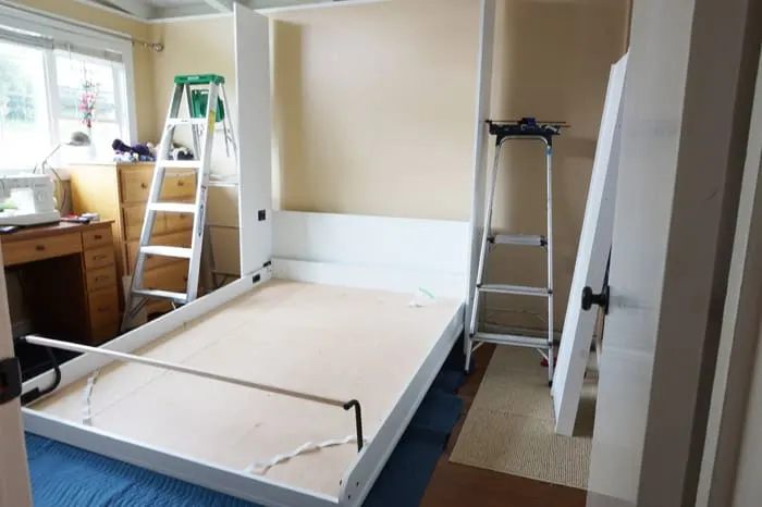 Ladders flank the partial assembly of the murphy wall bed