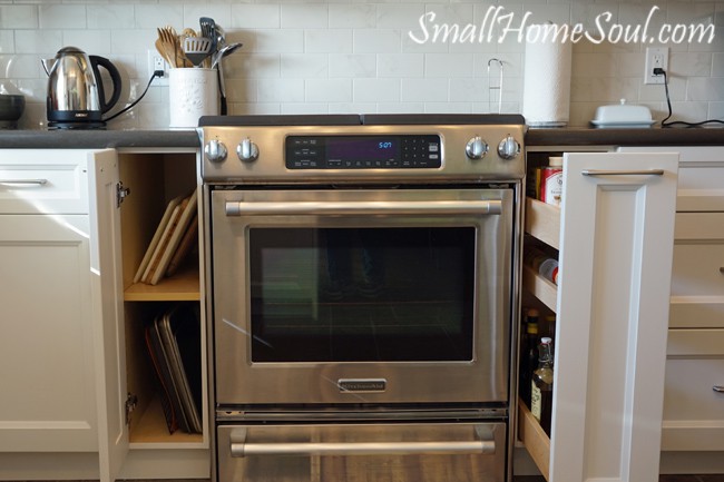 Stove side storage for cutting boards and cookie sheets on left side and oils and sprays on the right.