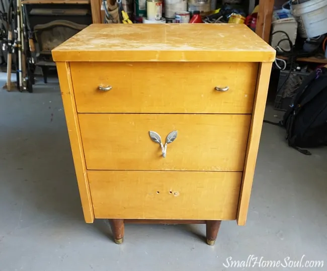 beat up 3-drawer little dresser missing knobs in garage.