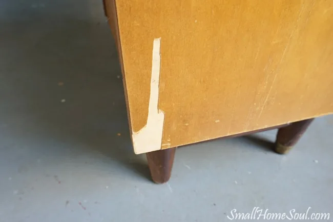 Side of mid-century modern dresser with missing veneer.