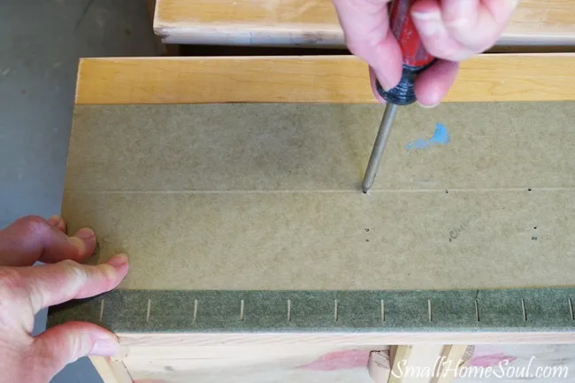 Poking a scratch awl into a green template on top of dresser drawer