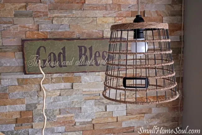 DIY Hanging light hanging in front of quarts wall and God Bless sign.