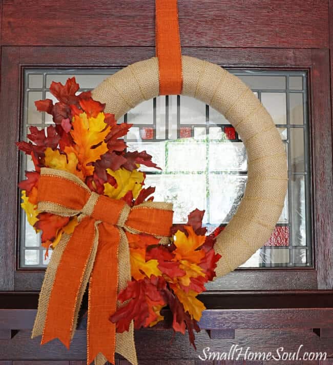 DIY Burlap Fall wreath hanging on front door with orange ribbon.