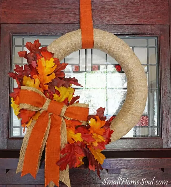 DIY Burlap Fall wreath hanging on front door with orange ribbon.