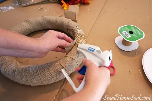 Hotgluing burlap ribbon to straw wreath form.