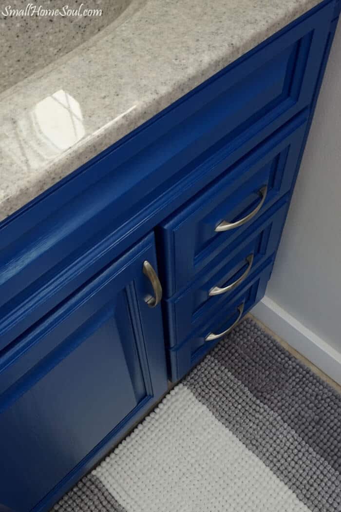 Top down view of newly painted blue bathroom vanity and gray and white rug.