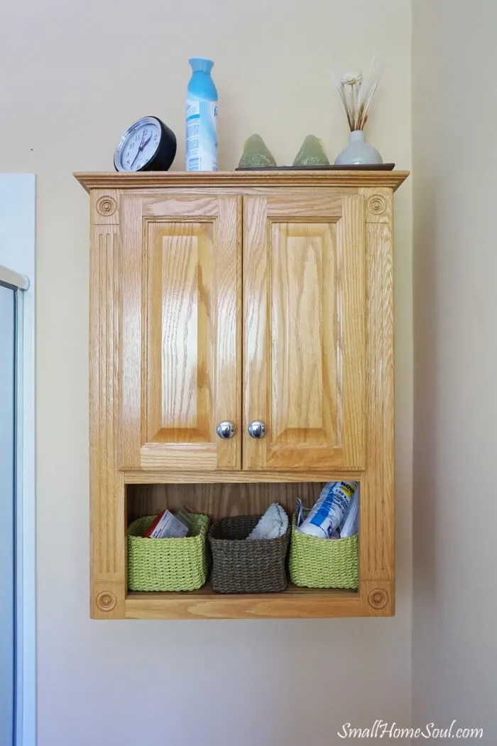 Before picture of oak toilet paper cabinet above toilet.