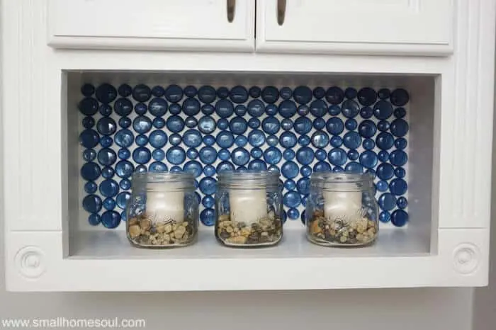 beautiful glass backsplash in blue inside TP shelf.