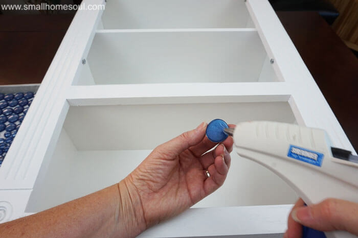 Glue gun and glue on blue bead for glass backsplash.