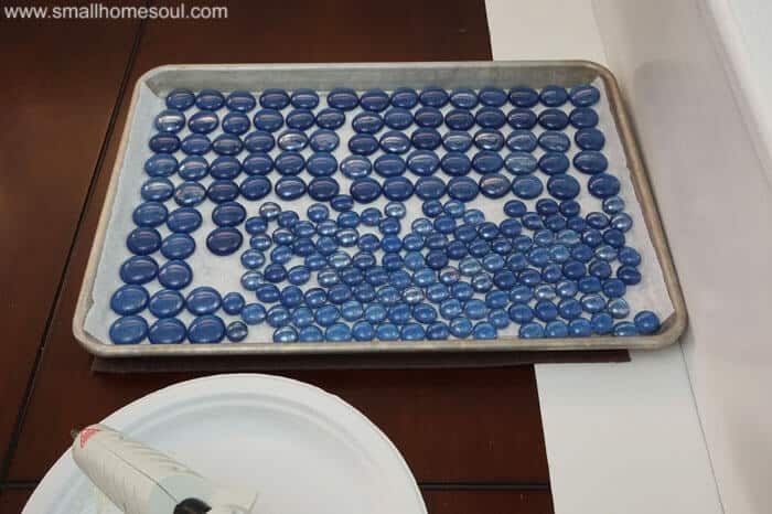 Glass beads painted blue on cookie sheet ready to install in glass backsplash .
