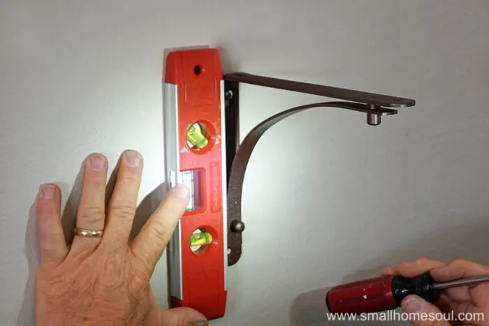 using a level to install a shelf bracket to the wall