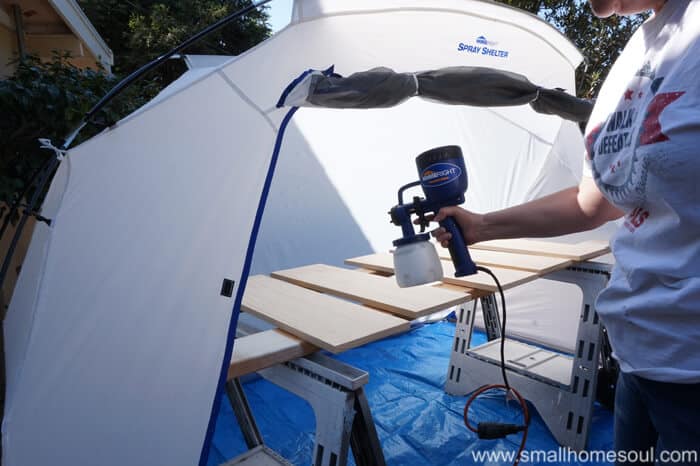 paint tent with shelves on sawhorses getting a coat of white paint.