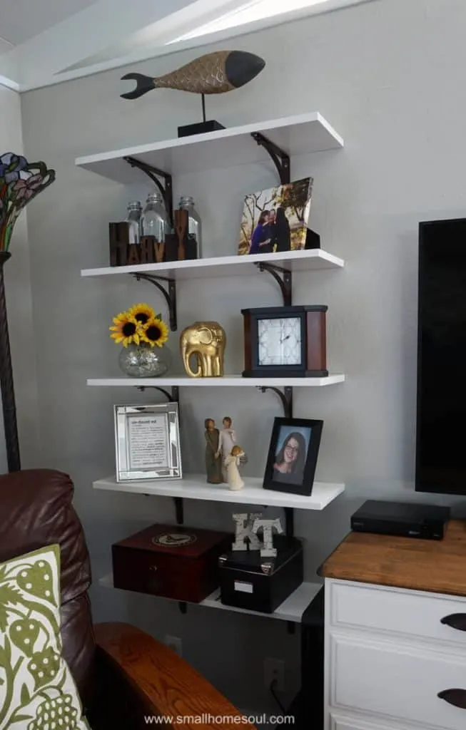 Green pillow in brown chair next to newly installed shelves next to TV