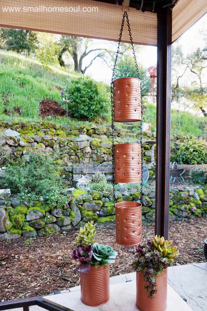 Recycled Tin cans as lights hanging on patio with recycled tin can planters below with succulents. 