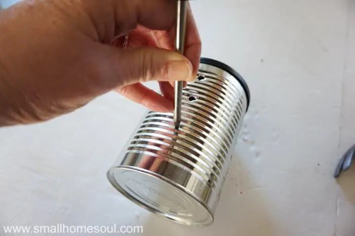 Poking holes into a tin can with an awl tool.