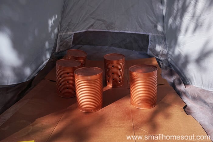 Spray painting tin cans with copper spray paint.
