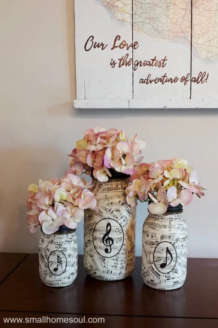 Music sheet mason jar vases filled with hydrangea on dining room buffet.