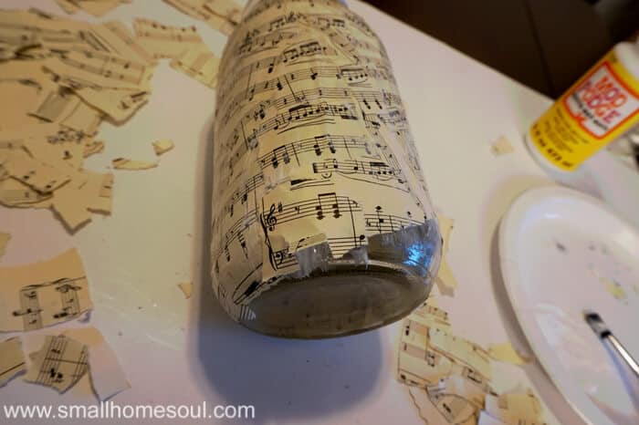 mason jar with torn sheet music decoupaged on sides.