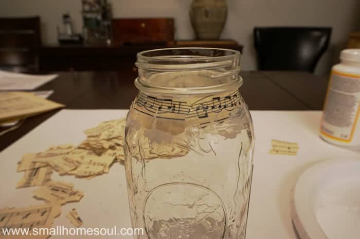 Mason jar with torn sheet music pages glued on.