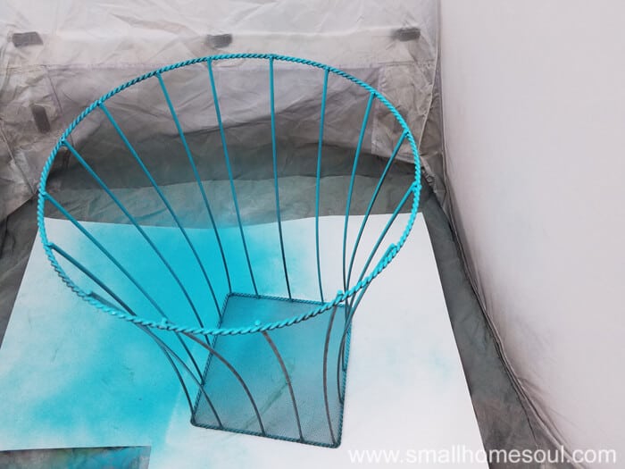 Spray painting blue the basket for the outdoor plant stand.