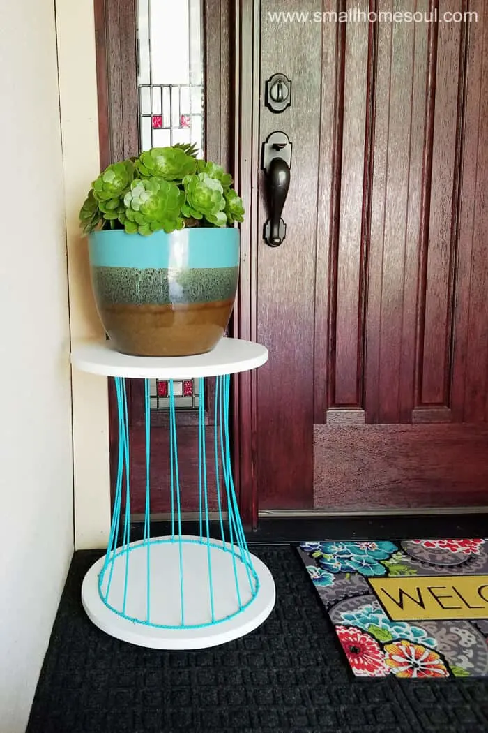 Pretty blue and white outdoor plant stand by front door on porch.