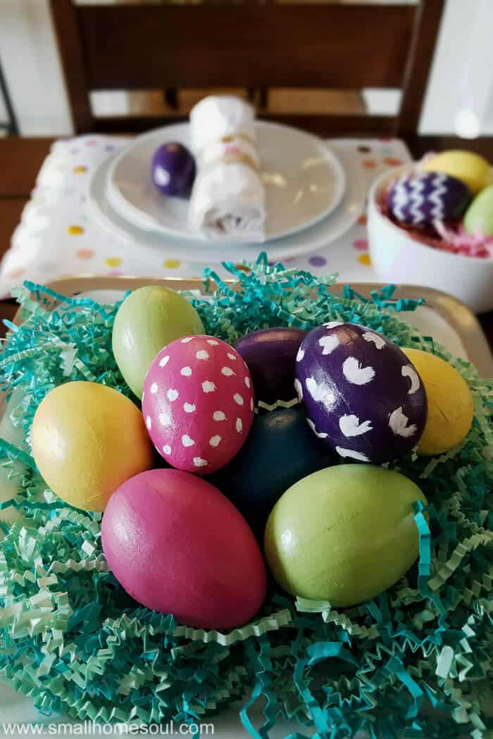 Easter table decorations with colorful eggs on a cake stand.