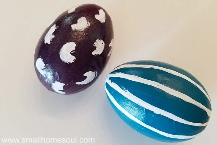 Grouping of cute and easy painted Easter eggs in purple and teal with strips and swipes painted on.