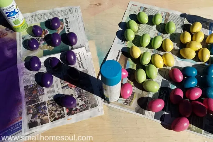 Spray painted eggs on newspaper in purple green, yellow, pink and teal.