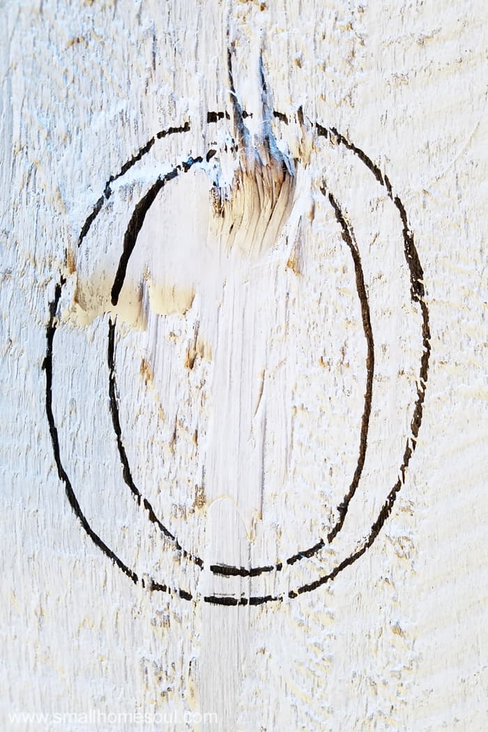 Letter O is outlined with paint pen on rough section of welcome sign.