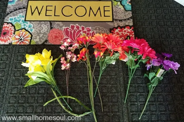 Fake flowers laid on doormat to arrange in bouquet.