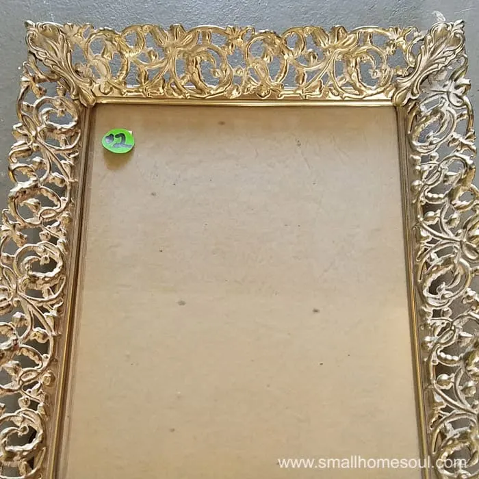 Old metal picture frame with no picture and a $2 green pricetag.