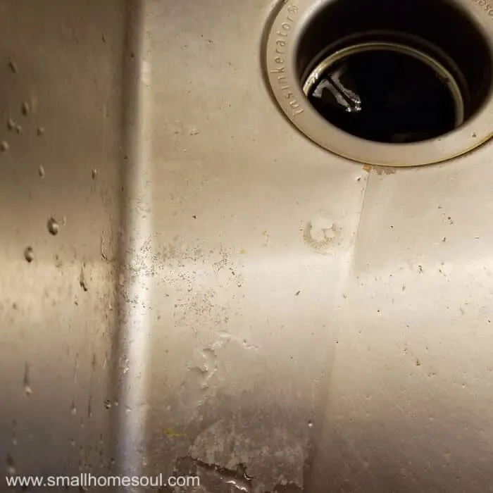 Sludge forms around the feet of the kitchen sink grid.