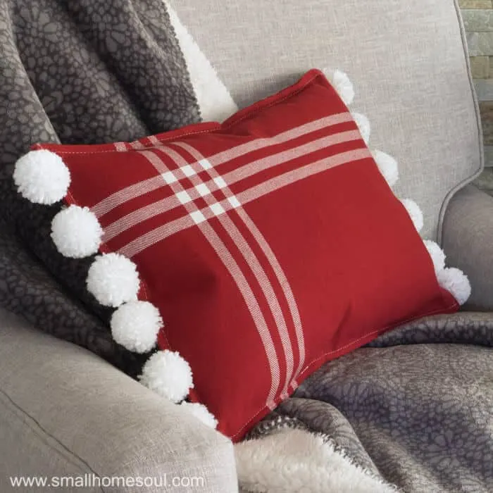 Finished Christmas Pom Pom Pillow in chair with throw.