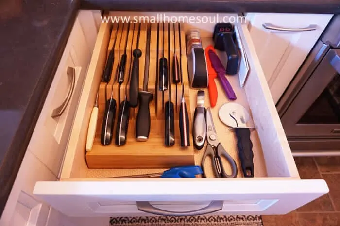 Kitchen knives stored in bamboo knife organizer and utensils that cut in one drawer.