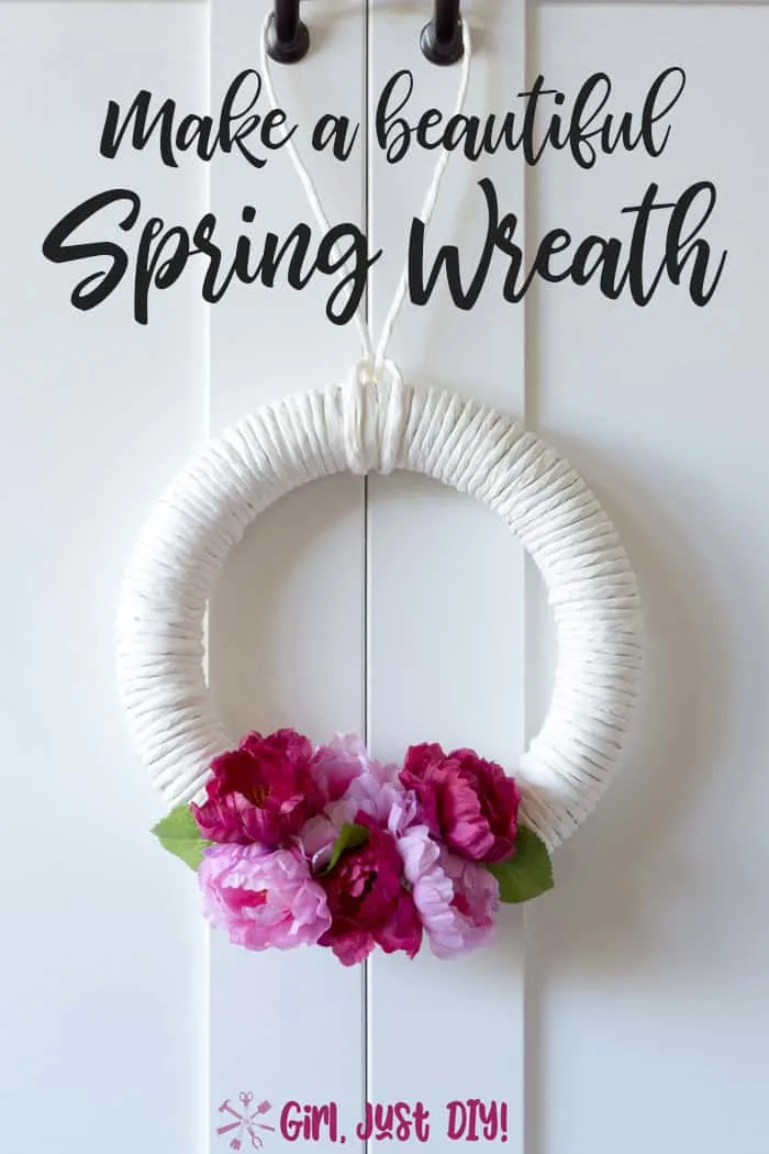 white wreath with dark and light pink flowers hanging on a white door.