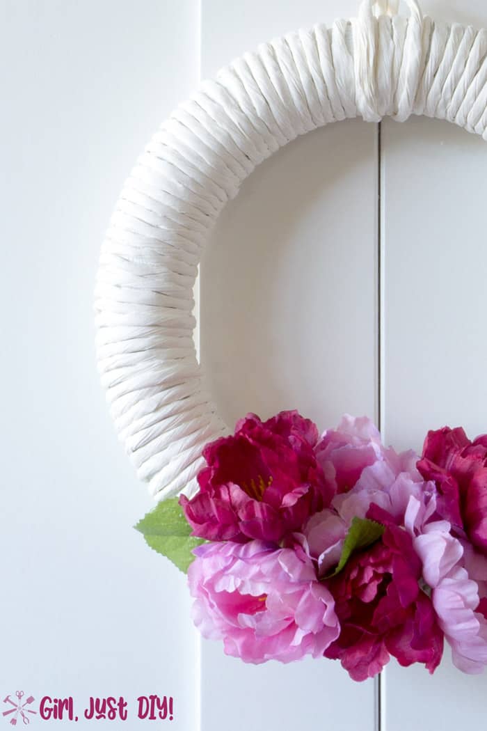 light and dark pink flowers on white wreath hanging on white door