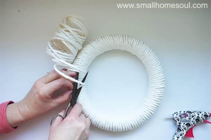 Cutting and gluing paper twist onto diy spring wreath.