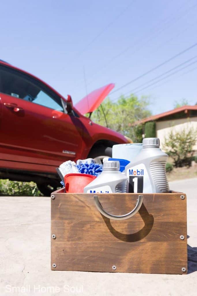 Oil change kit on driveway with car hood up.