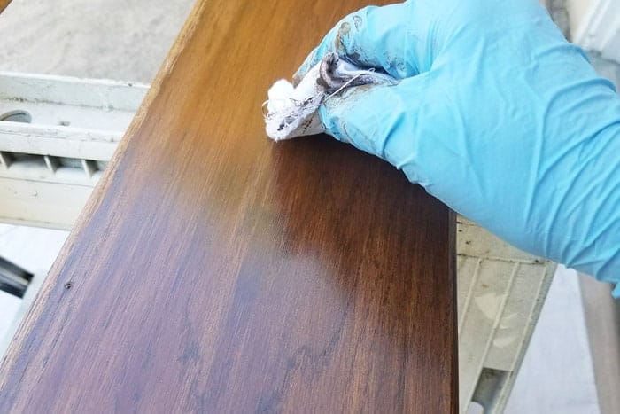 Wiping excess stain from floating wood shelves.