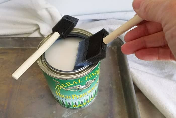 applying top coat with foam brush on floating wall shelves.