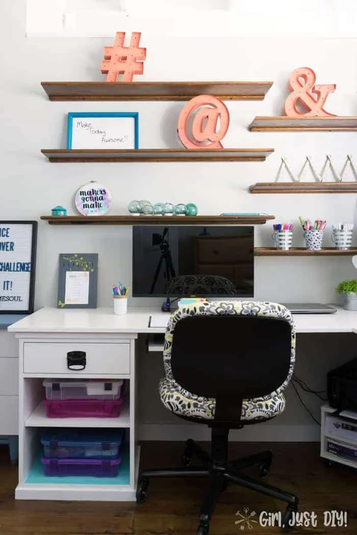 Floating wood shelves over new l-shaped desk in office.