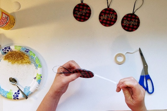 Double sided tape applied to edge of buffalo check ornaments.