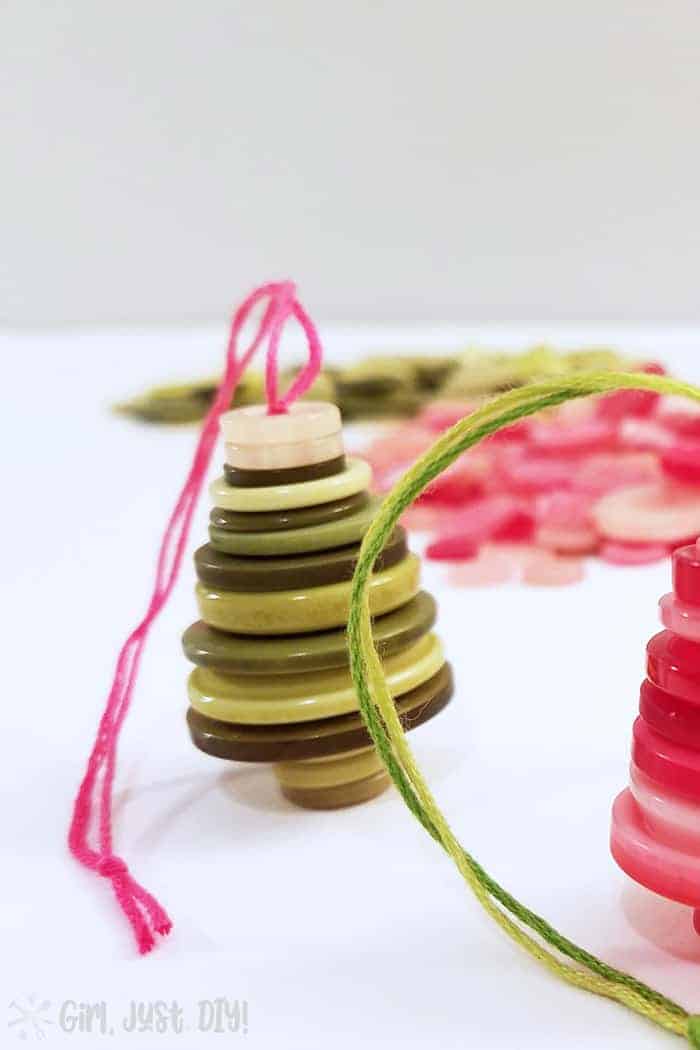Green button Christmas tree ornament with pink floss string.