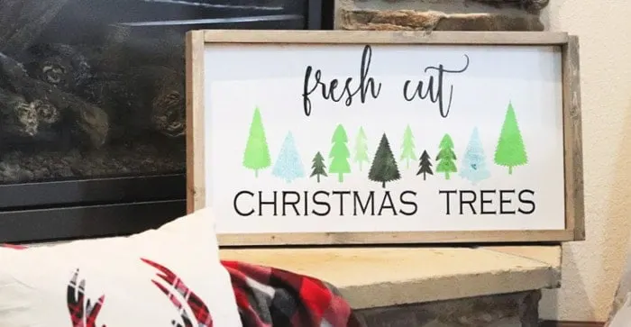 Fresh cut christmas tree sign with green and blue forest trees.