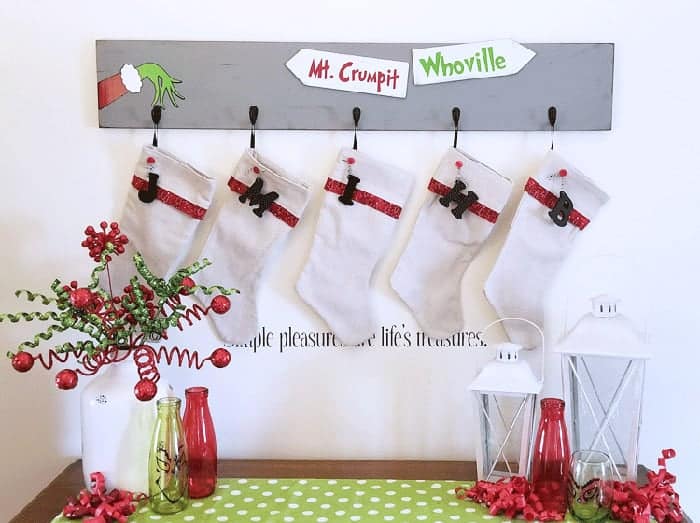 Grinch stocking holder on wall with stockings.