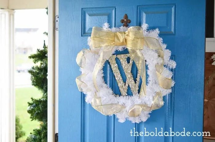 White and gold sparkly christmas wreath hung on blue door.