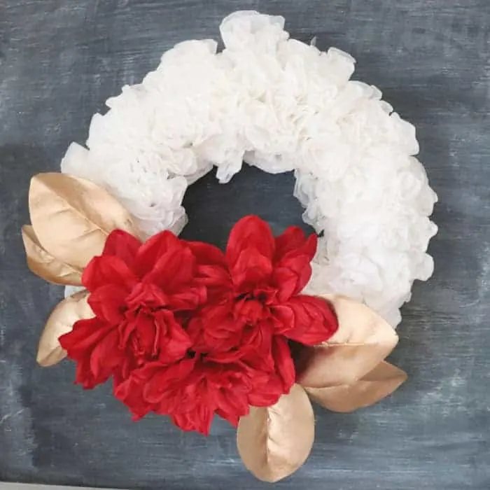 sparkly christmas wreath with gold leaves and red flowers on a coffee filter wreath.