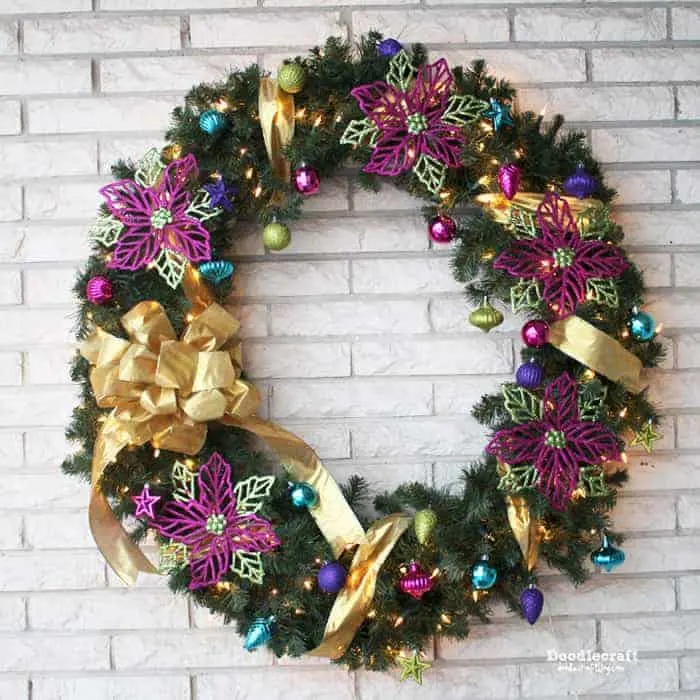 green and purple sparkly christmas wreaths on a brick wall.